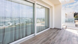 Ein modernes Zimmer mit großen Schiebeglastüren, Holzboden und Blick auf eine Marina.