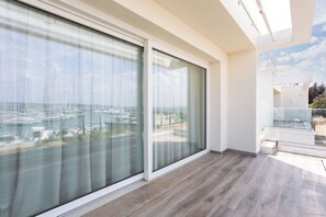 A modern room with large sliding glass doors, a wooden floor, and a view of a marina. - Porto di Luce by Geco Vacation Rentals (Scarlino)