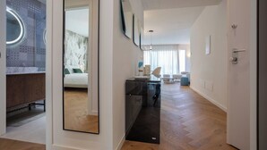 Ein modernes Hotelzimmer mit einem großen Spiegel, einem Bett, einem Schreibtisch und einer Sitzecke.