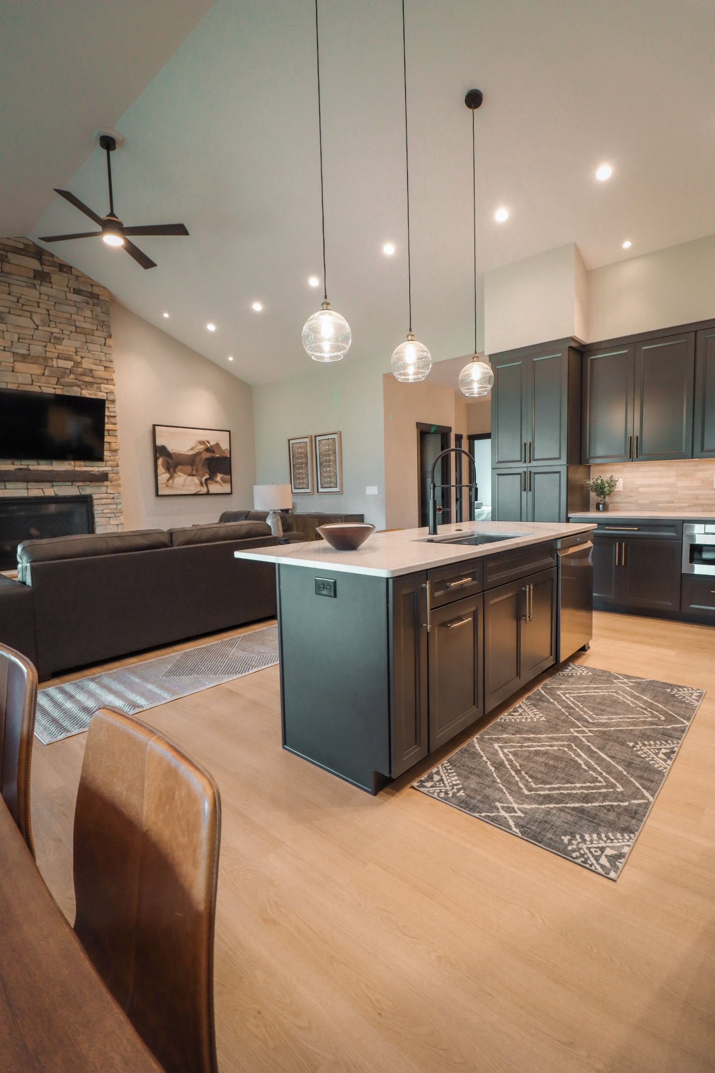 A modern kitchen with a central island, dark cabinetry, and pendant lighting.