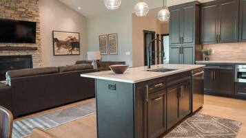 A modern kitchen with a central island, dark cabinetry, and pendant lighting.
