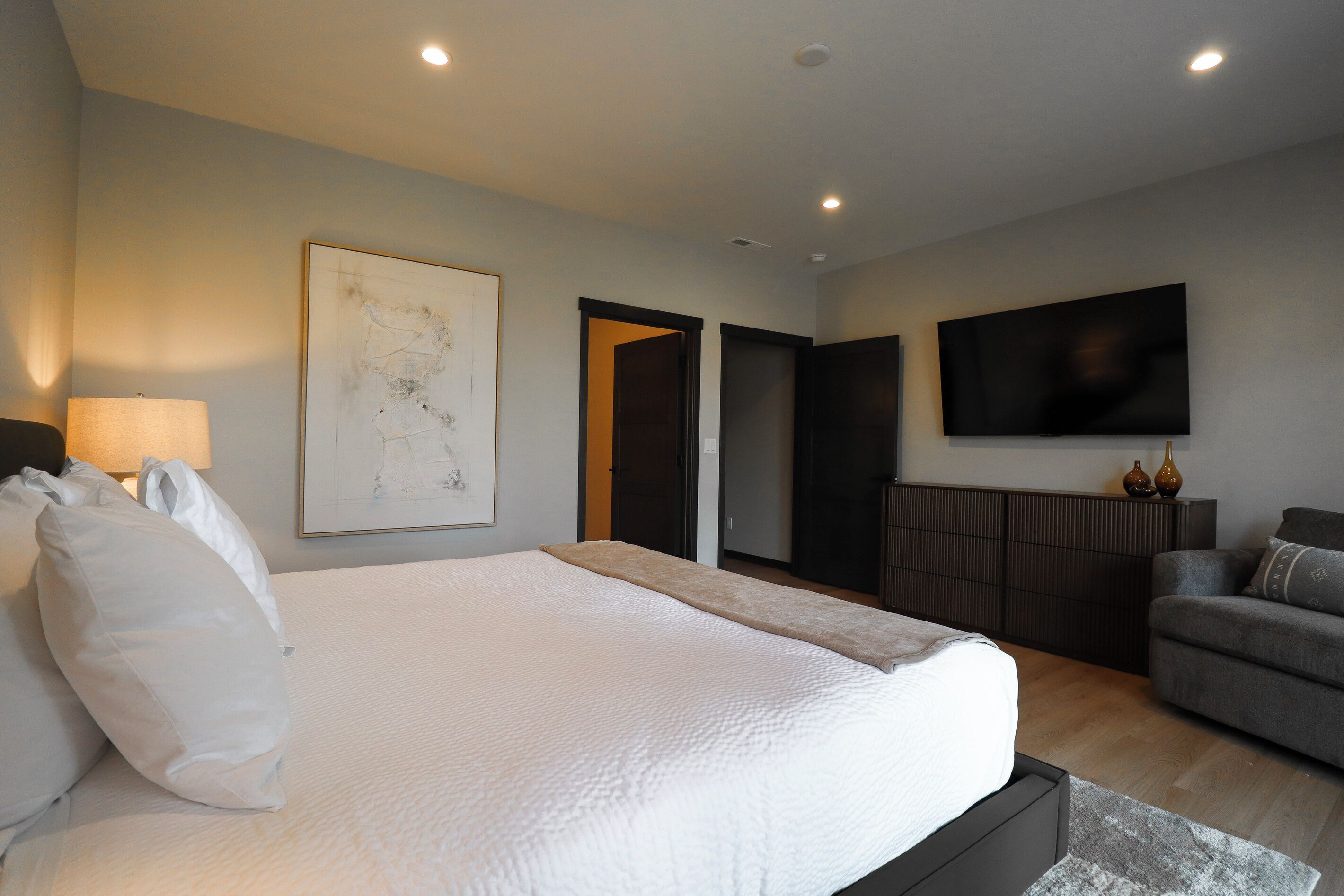 A modern hotel room with a large bed, a flat-screen TV, and a minimalist decor.