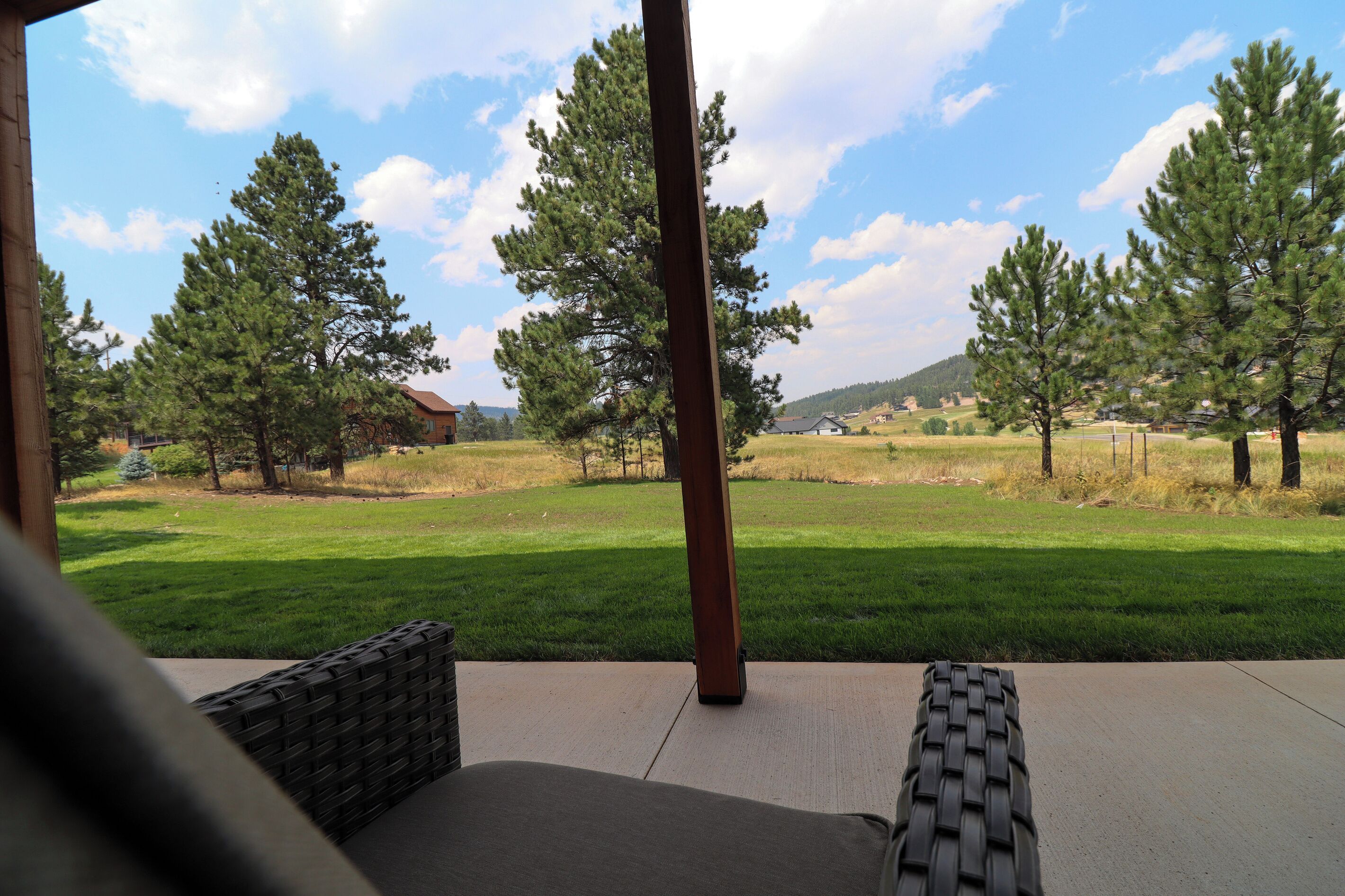 An outdoor patio with a view of a grassy field and trees.