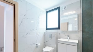 Une salle de bain avec des toilettes, un lavabo, un miroir et une fenêtre.
