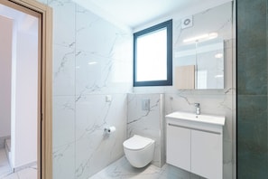 Un baño con inodoro, lavabo, espejo y ventana.