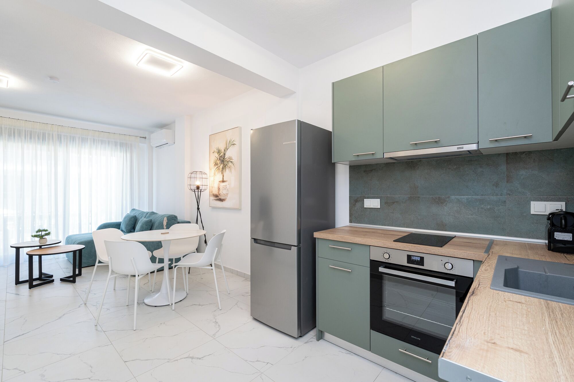 A modern kitchen with a built-in oven, a refrigerator, and a dining area with a table and chairs.