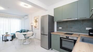A modern kitchen with a built-in oven, a refrigerator, and a dining area with a table and chairs.