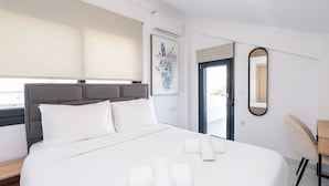 Une chambre d’hôtel avec un lit, une fenêtre donnant sur un paysage agréable, une porte et un miroir fixé au mur.