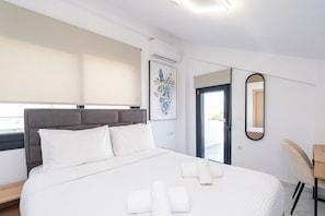 Habitación de hotel con cama, ventana con vistas, puerta y espejo adosado a la pared.