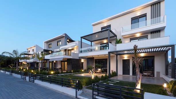 Un immeuble résidentiel moderne doté de nombreux balcons, d’un jardin bien entretenu et d’une allée pavée.