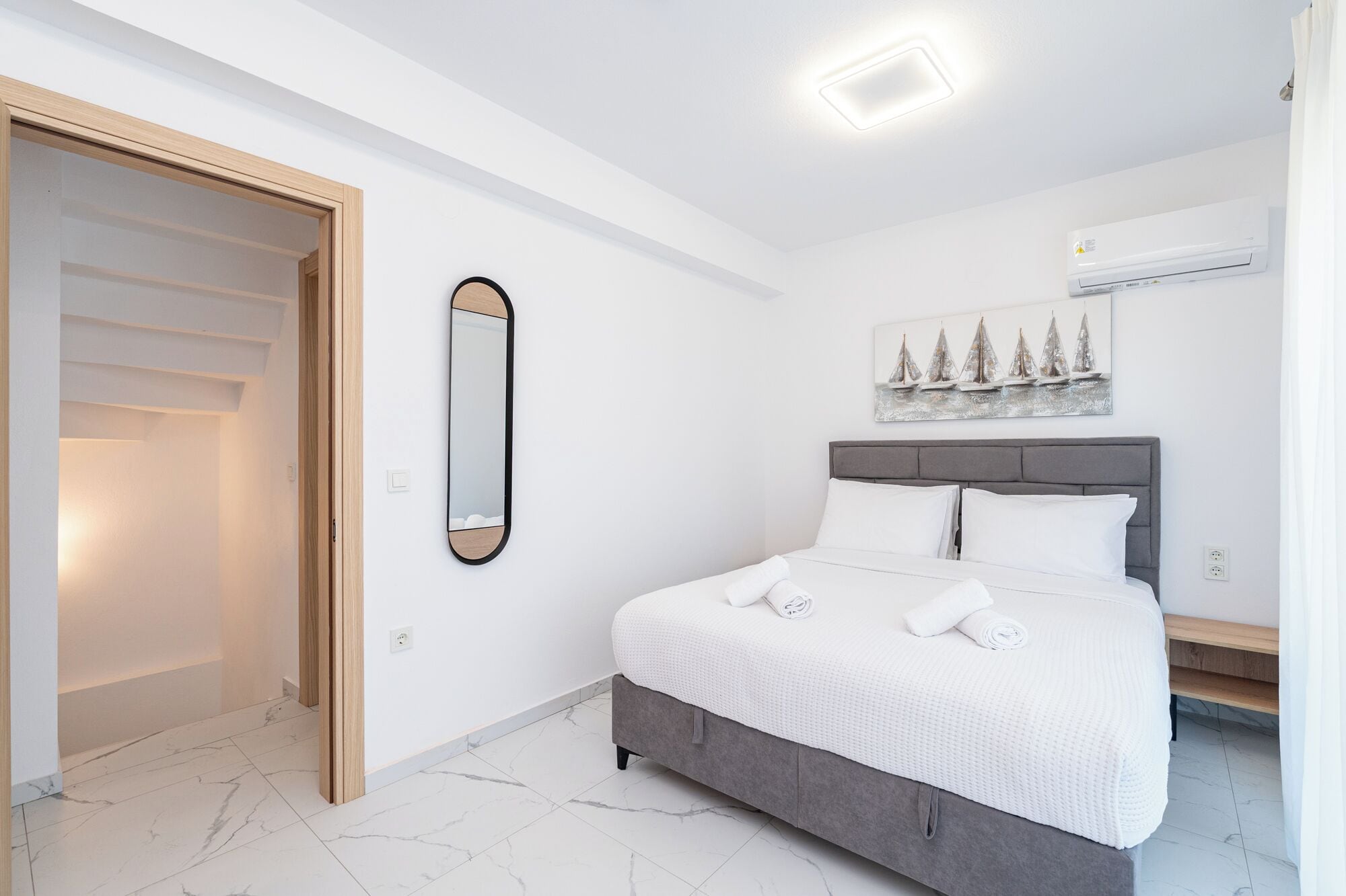 Un dormitorio con cama, espejo, cuadro y una lámpara en el techo.