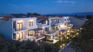 Un immeuble résidentiel moderne à plusieurs étages, doté de balcons et d’un jardin aménagé.