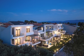 Un edificio residencial moderno de varios pisos con balcones y un jardín ajardinado.