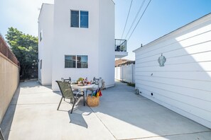 Ein weißes Gebäude mit Balkon, einem Tisch mit Stühlen und einem Korb auf der Terrasse.