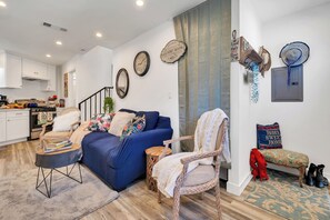 A living room with a blue sofa, a patterned armchair, a small wooden stool, and a bench with a cushion. - Chic 3-bedroom Modern Home Near SoFi Stadium & LAX, Comfortable with AC & WIFI (Inglewood)