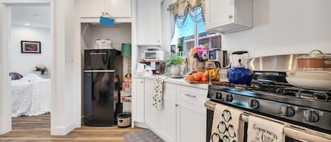 A modern kitchen with white cabinets, a stainless steel stove, and a refrigerator.