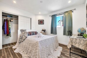 Ein Schlafzimmer mit einem Bett, einem Kleiderschrank, einem Nachttisch, einem Fenster mit Vorhängen und einem kleinen Tisch mit Globus.
