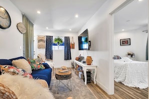A modern living room with a sofa, coffee table, TV, and a separate bedroom area with a bed. - Chic 3-bedroom Modern Home Near SoFi Stadium & LAX, Comfortable with AC & WIFI (Inglewood)