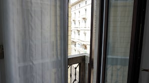 A view through a window with a balcony, featuring a building with classical architecture. - Piazza Duomo Exclusive Family Apartment (Milano)