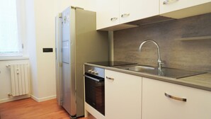 A kitchen with a built-in oven, a stainless steel sink, and a window with blinds. - Piazza Duomo Exclusive Family Apartment (Milano)