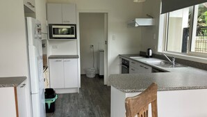 Eine moderne Küche mit weißen Schränken, einer Mikrowelle, einem Spülbecken und einem Fenster.