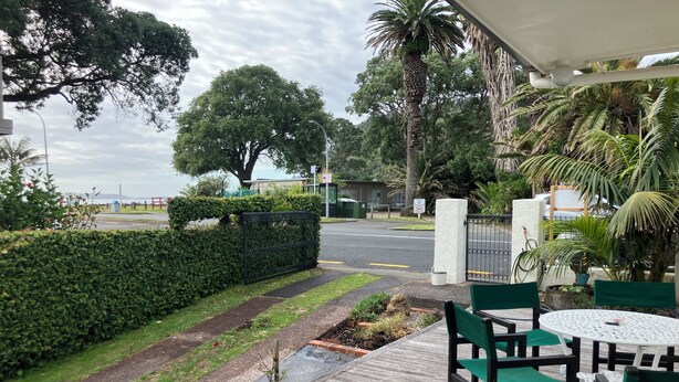 Eine Terrasse mit Holzboden, grünen Stühlen und einem Tisch.
