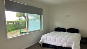 Ein Schlafzimmer mit einem Bett, einem Fenster und Blick auf eine grüne Landschaft.