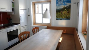Et køkken med spisebord, stole, en hængende lampe og et vindue.