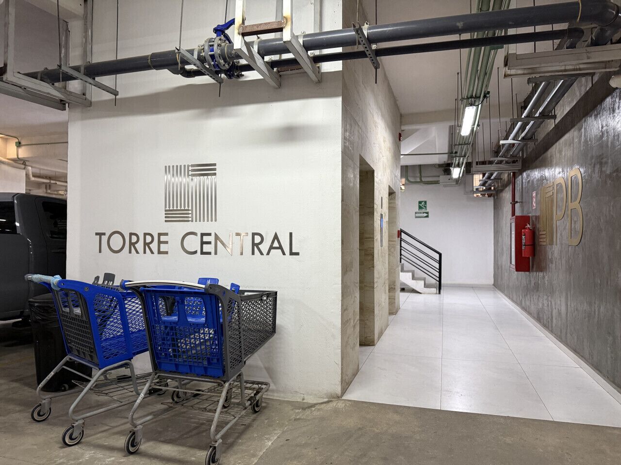 A shopping cart area with a sign reading 'TORRE CENTRAL' and a staircase leading to an upper level.