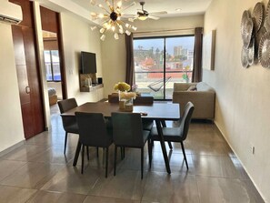 A modern living room with a dining area, a large window with a view, and a ceiling fan. - Near the beach, in the heart of the Golden Zone (Mazatlán)