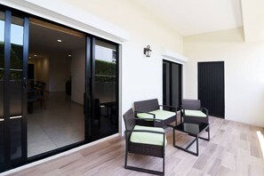 Eine moderne Außenpatio mit Schiebeglastüren, die zu einem Essbereich führen, mit Korbstühlen und einem Tisch möbliert.
