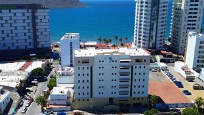 Un hôtel à plusieurs étages offrant une vue sur l’océan et sur une montagne en arrière-plan.