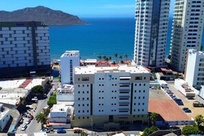 Ein mehrstöckiges Hotel mit Blick auf das Meer und einem Berg im Hintergrund.