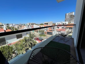 Ein Balkon mit freiem Blick auf die Stadtlandschaft, ein Stuhl und eine kleine Rasenfläche.