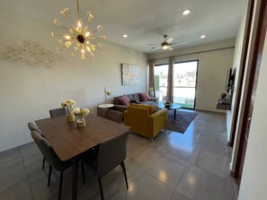 Ein modernes Wohnzimmer mit Essbereich, einer Couch, einem Couchtisch und einem Deckenventilator.