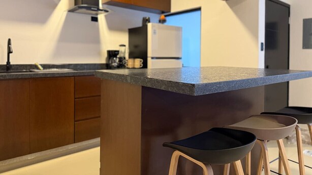 Una cucina moderna con mobili in legno, un piano di lavoro in granito e sgabelli da bar.