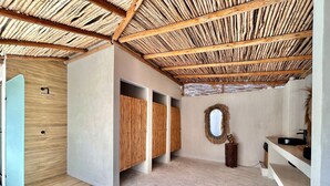 Ein Zimmer mit Strohdach, Holzschränken, Steinböden und einem Spiegel an der Wand.