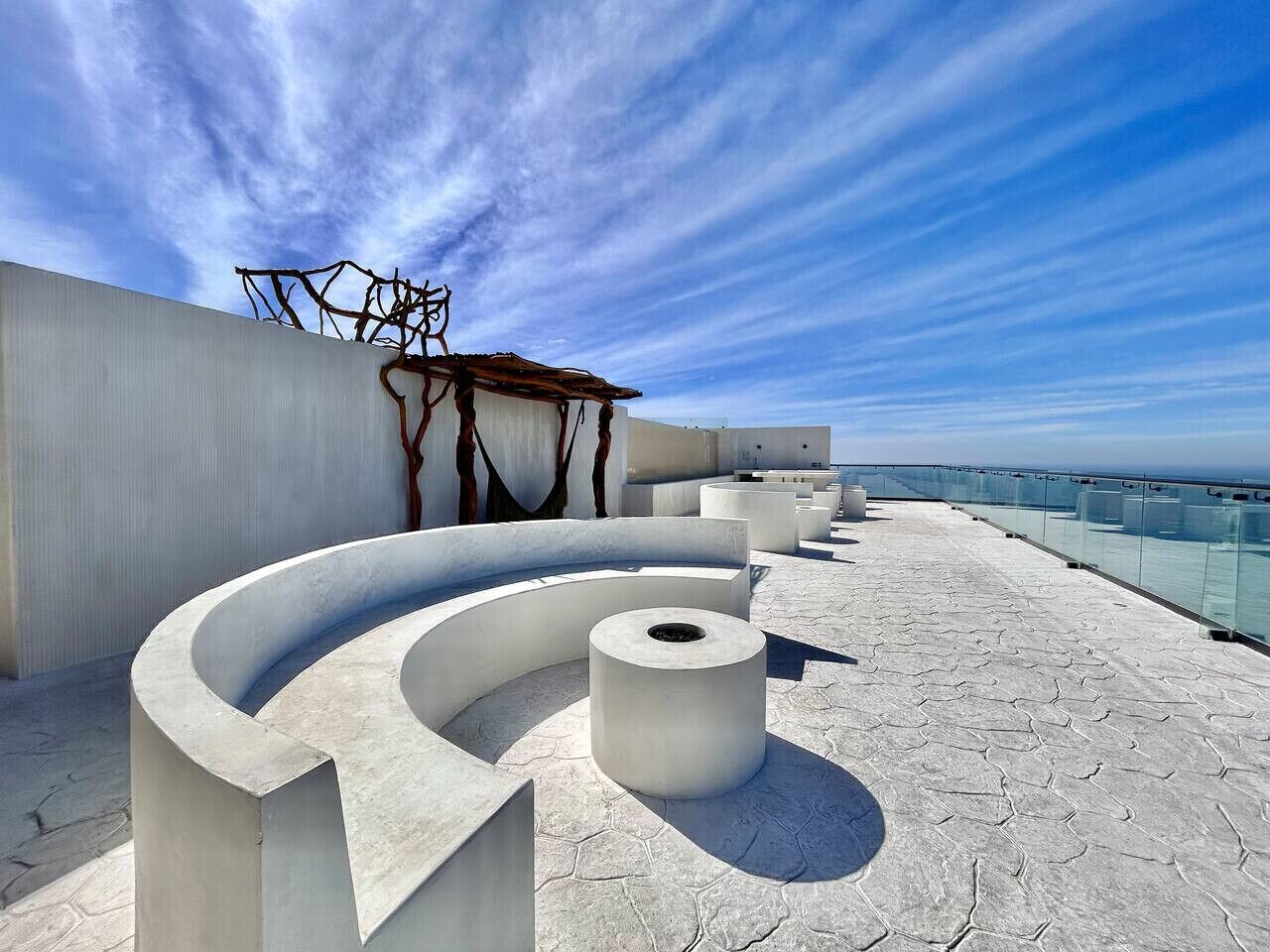 A rooftop terrace with a curved seating area and a cylindrical structure.