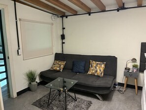 A modern living room with a sofa, a glass coffee table, a small side table with a lamp, and a potted plant. - Casa con Alberca en Centro by GPS (Mazatlán)