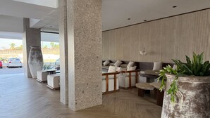 Eine moderne Lobby mit Sitzgelegenheit, einer großen Topfpflanze und Blick ins Freie.