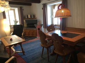 A cozy dining area with a wooden table and chairs, a television, and a decorative lamp. - Mugliner 117A, (Ftan) by Interhome (Ftan)