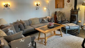 Een gezellige woonkamer met een bank, fauteuils, een salontafel en een open haard.