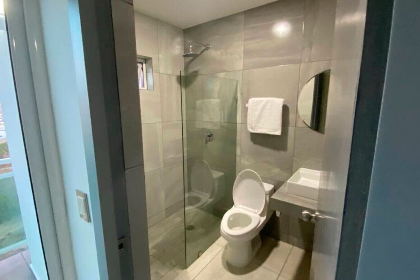 A modern bathroom with a glass-enclosed shower, a toilet, and a sink.