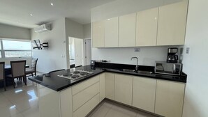 A modern kitchen with white cabinets, a black countertop, and a built-in microwave. - Departamento Premium Torre M by GPS (Mazatlán)
