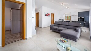 A modern living room with a grey sofa, a glass coffee table, and a kitchen in the background. - Amazing home in Pazin (Pazin)