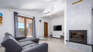 A modern living room with a fireplace, a flat-screen TV, and a sofa. - Amazing home in Pazin (Pazin)