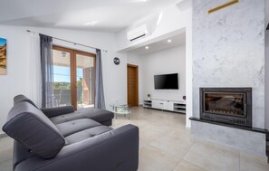 Ein modernes Wohnzimmer mit Kamin, Flachbildfernseher und einer Couch.