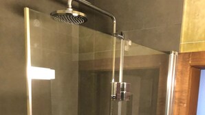 A glass-enclosed shower stall with a handheld showerhead, a wall-mounted faucet, and a chrome shower tray. - Mugliner 117A, (Ftan) by Interhome (Ftan)