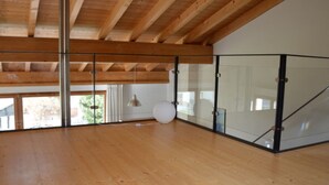 Quarto espaçoso com piso de madeira, divisória de vidro e uma janela grande.