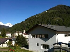 Ein Wohngebäude mit Satteldach, Schornstein und einer kleinen Veranda.